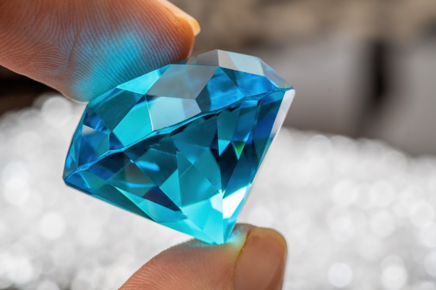 A hand of a man holding a shining blue gem