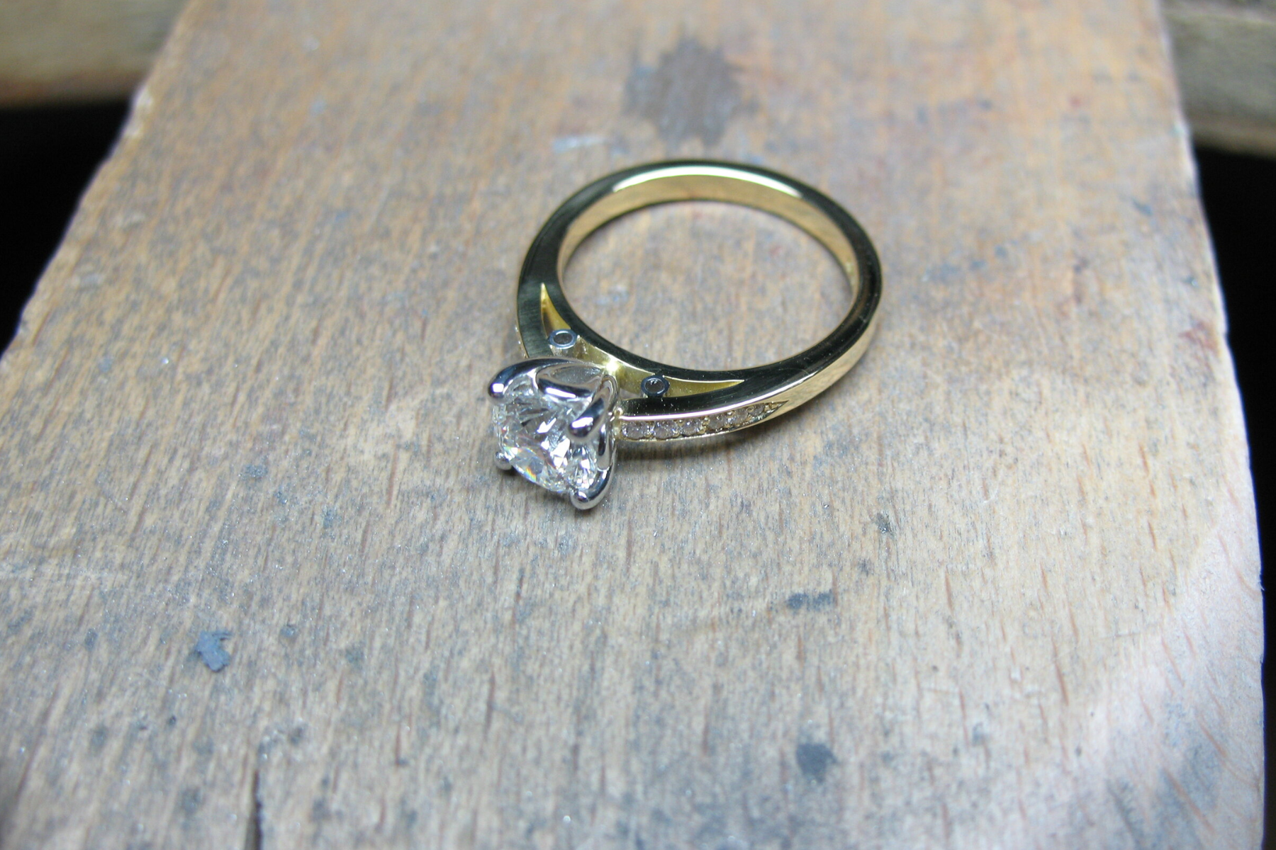 A handcrafted diamond ring on a wooden table