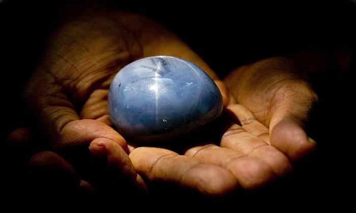 The world's largest star sapphire ever found placed on hand in dark background
