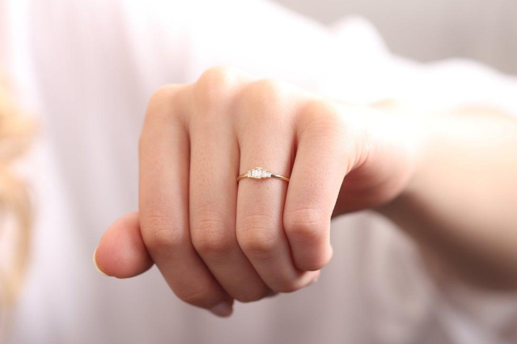 A woman's ring finger with a minimal wedding band