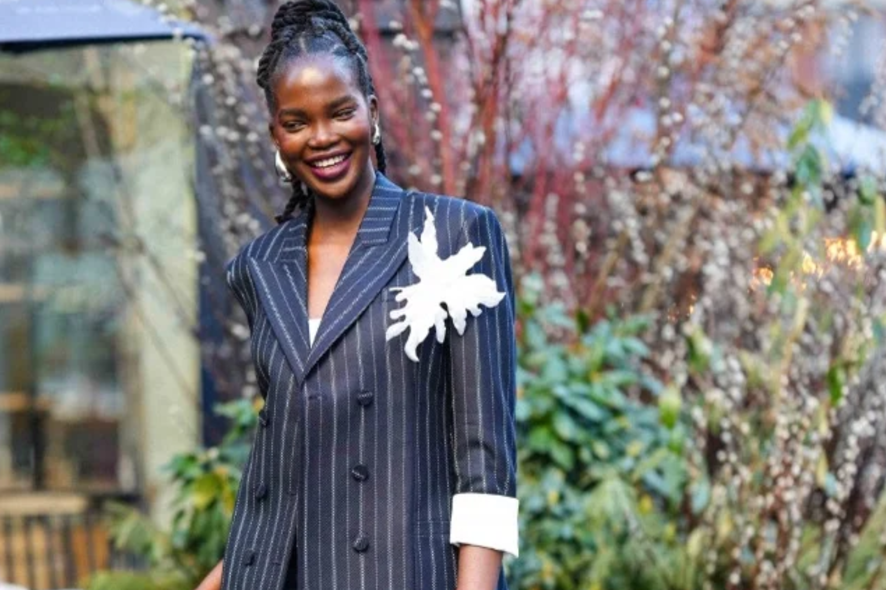 A stunning black woman is smiling while wearing a white feather brooch