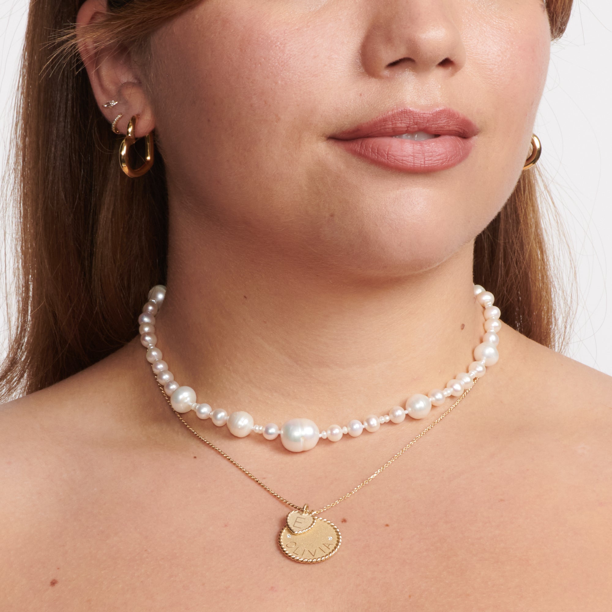 A woman wearing a Pearl sundry necklace together with another gold plated necklace