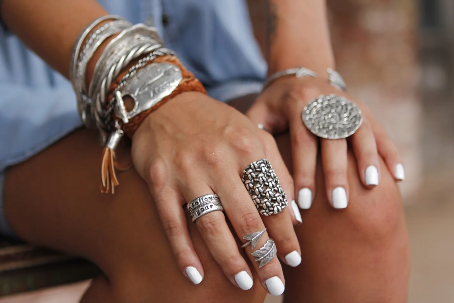 A woman wearing boho jewelry and supporting her knees