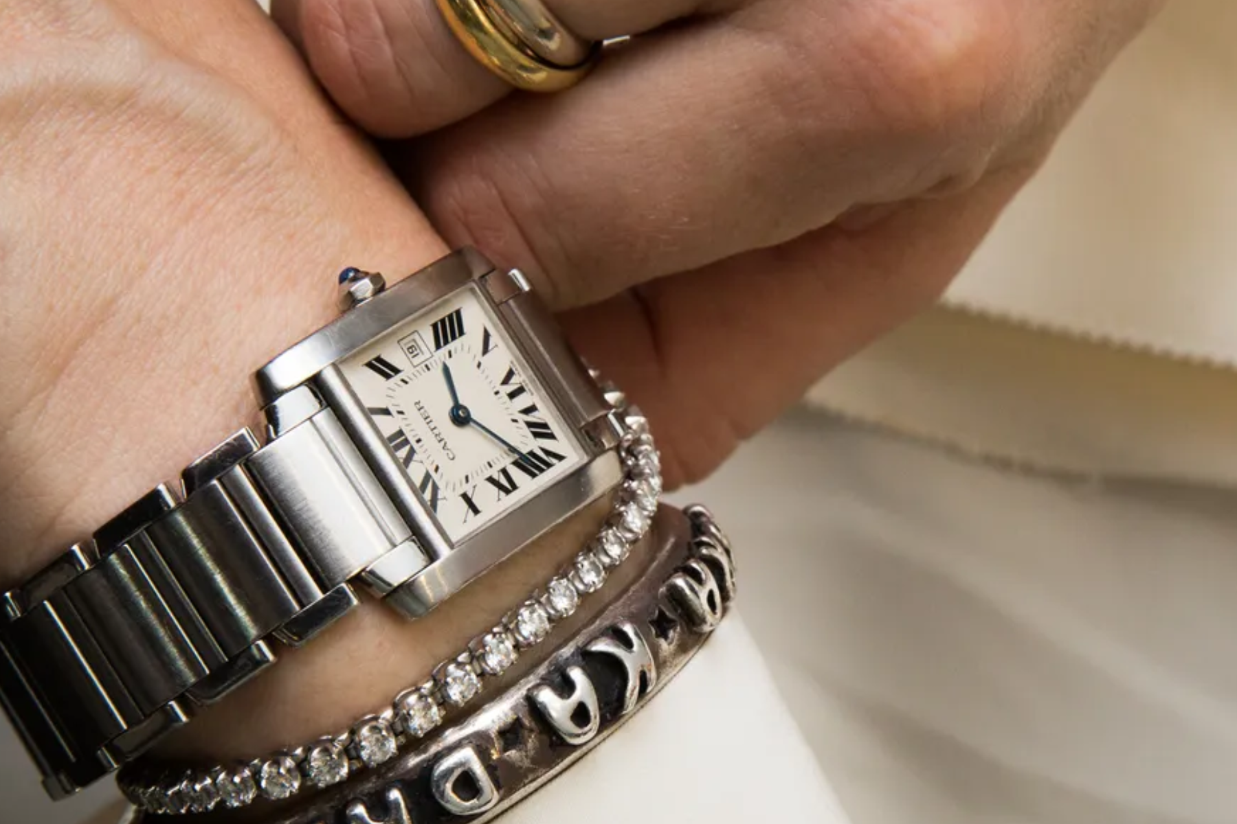 A man's wrist is adorned with a diamond watch and bracelets