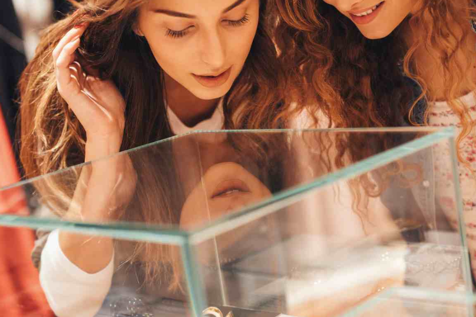 Inside the jewelry glass box, two women select a piece of jewelry