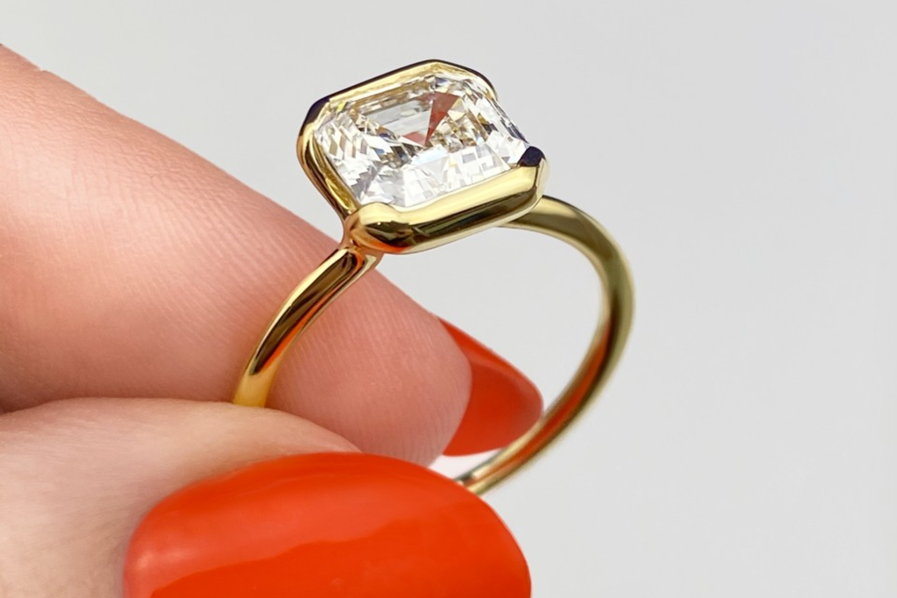 A woman's hand holding a ring in a bezel setting