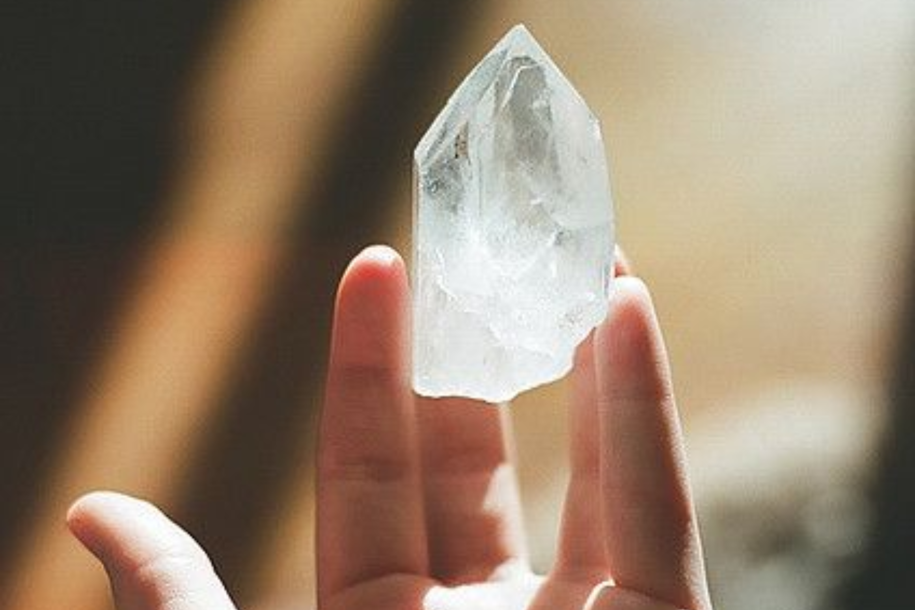 A person's hand raising a clear crystal