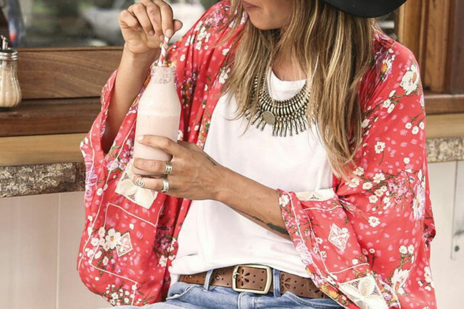 A woman drinking while wearing vintage bohemian jewelry