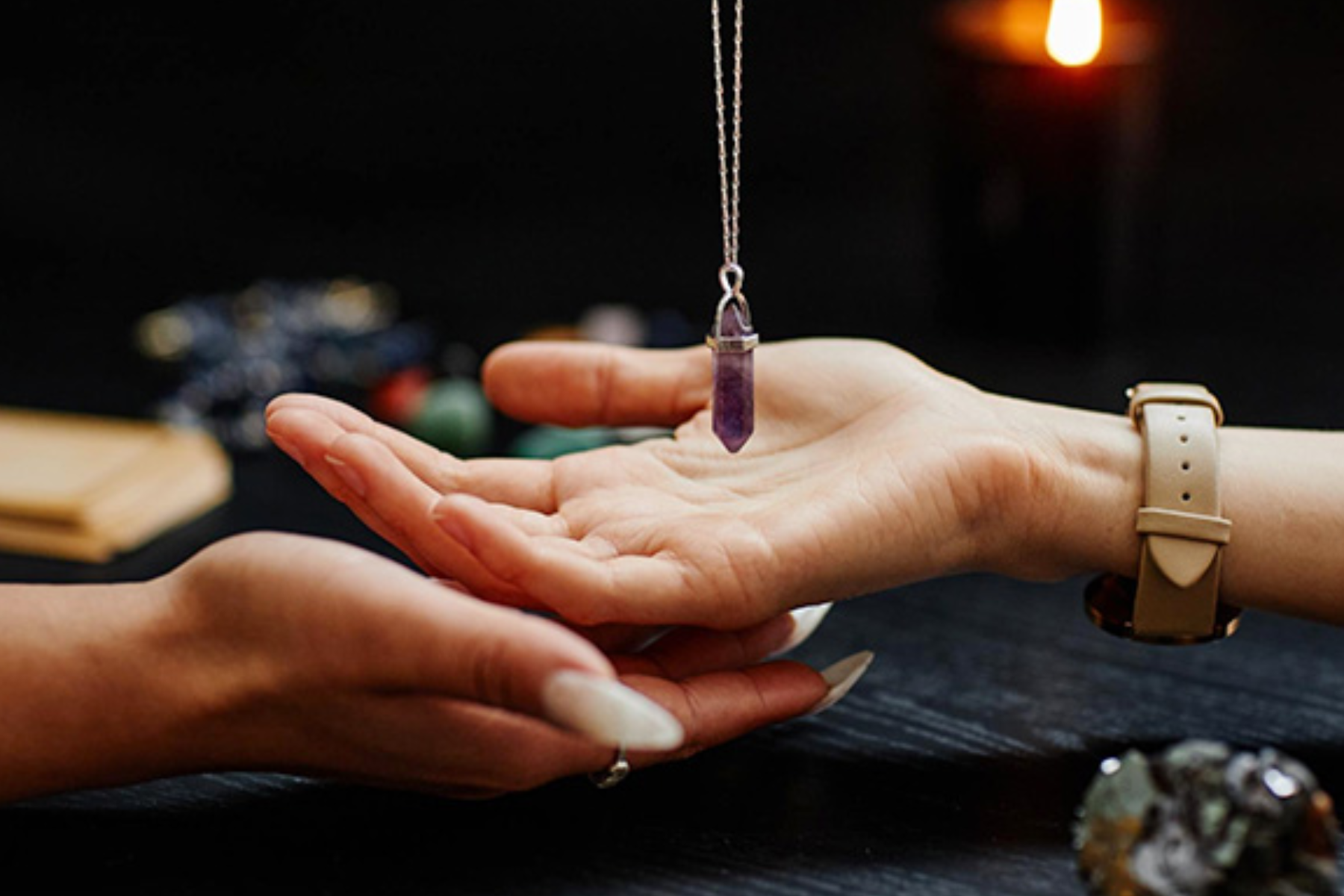 A woman's palm with an amethyst pendulum