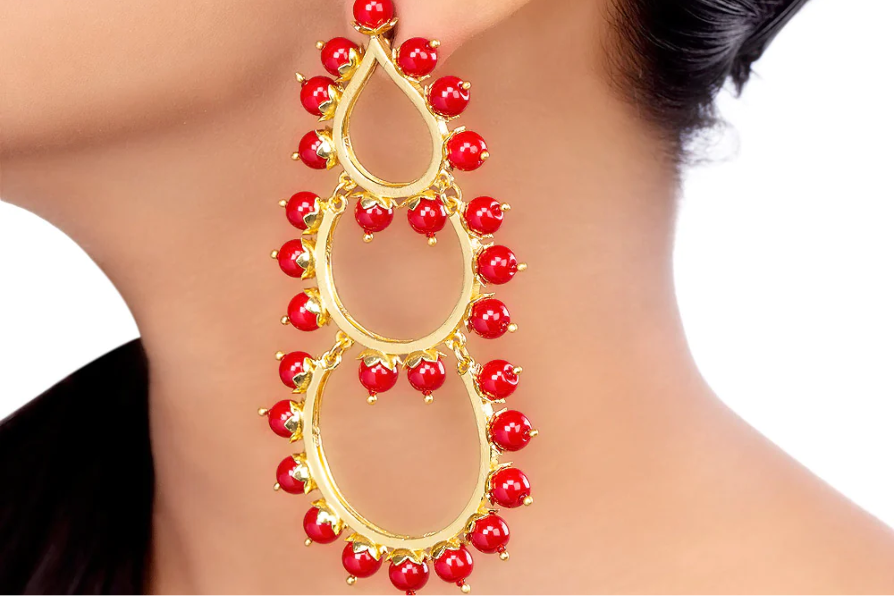 A woman sporting red jewels with gold earrings
