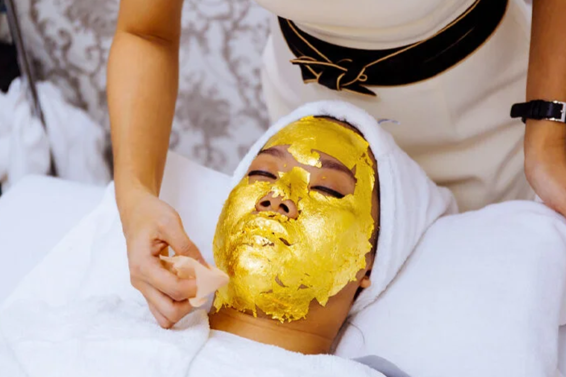 A woman receiving a facial treatment that includes gem-infused face masks