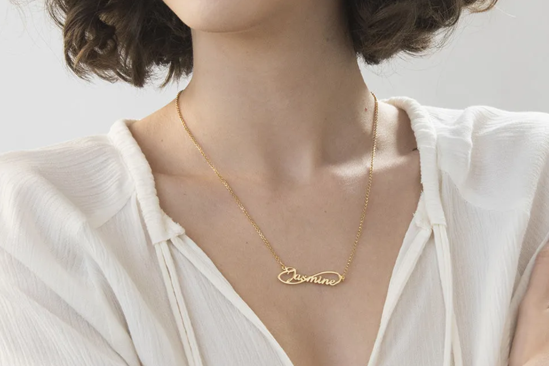 A woman wearing a gold endless pendant with her name engraved on it