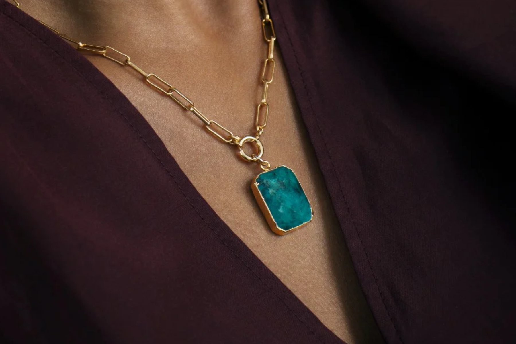 A woman wearing a necklace with a blue birthstone