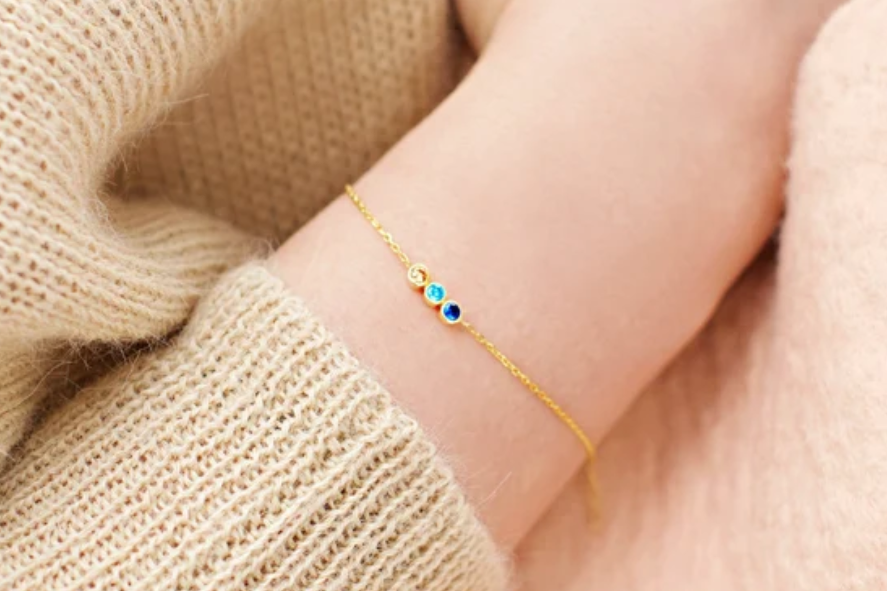 A woman wears a bracelet with three little birthstones