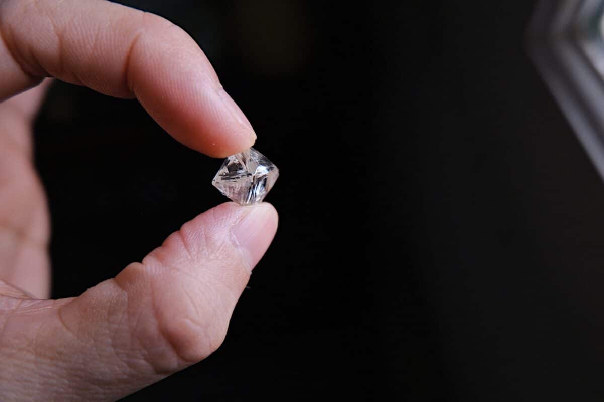 A hand holding a rough diamond
