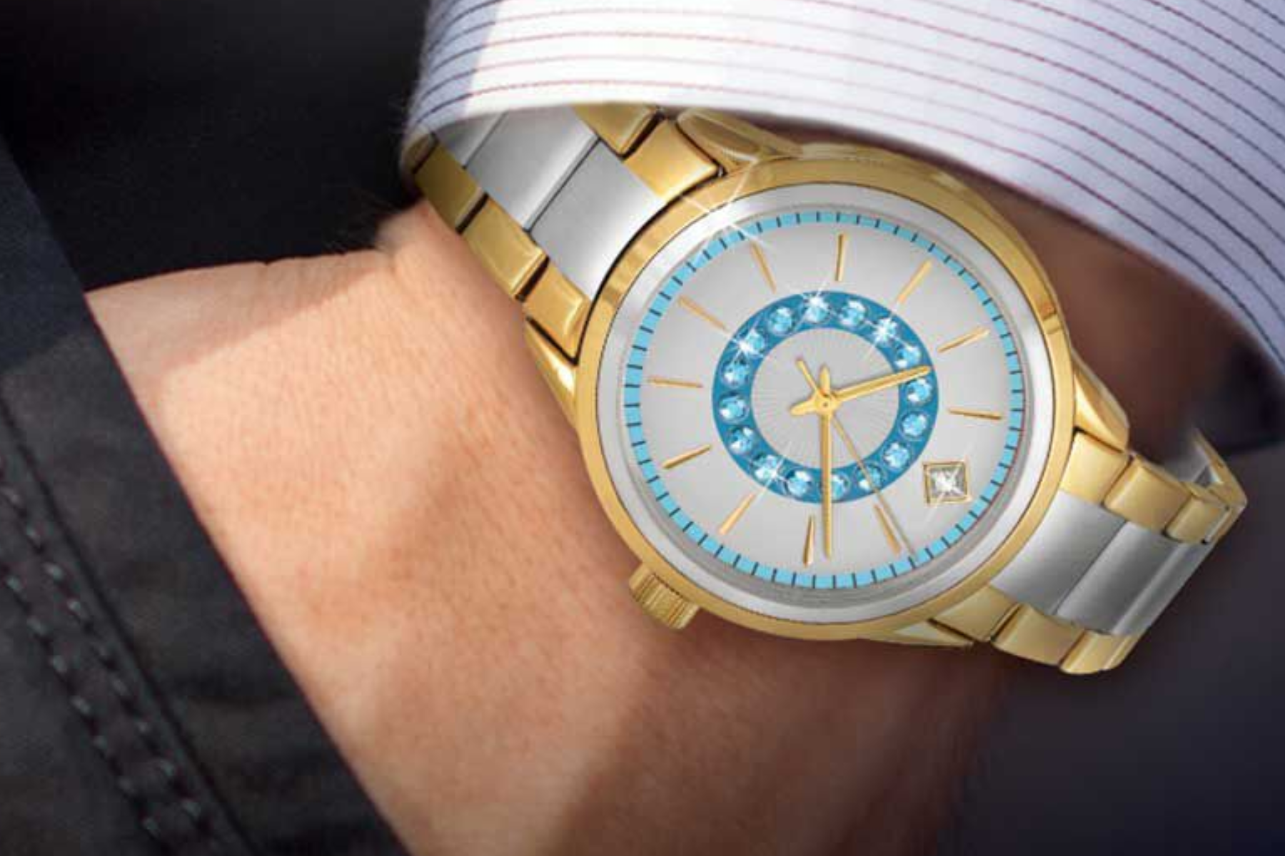 A man's wrist is adorned with a gold timepiece that contains blue birthstones