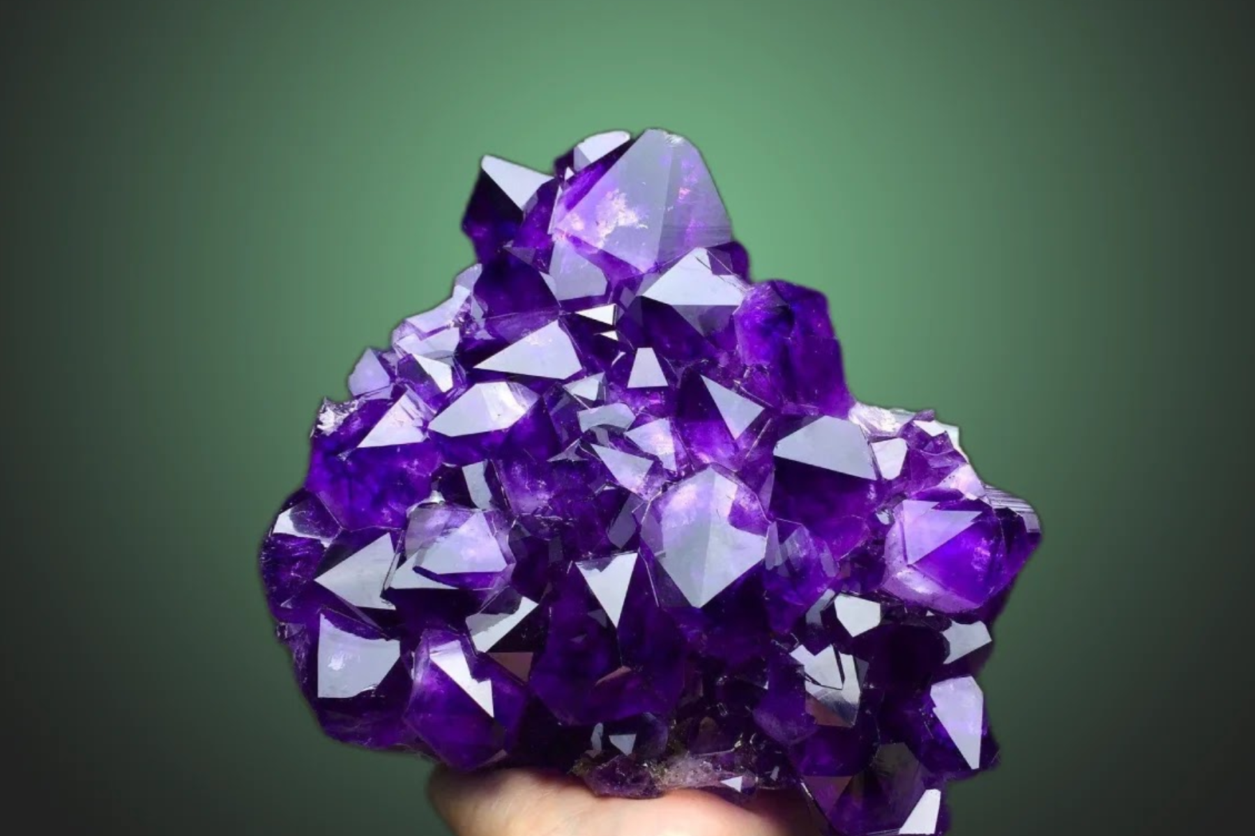 A large raw amethyst in a hand