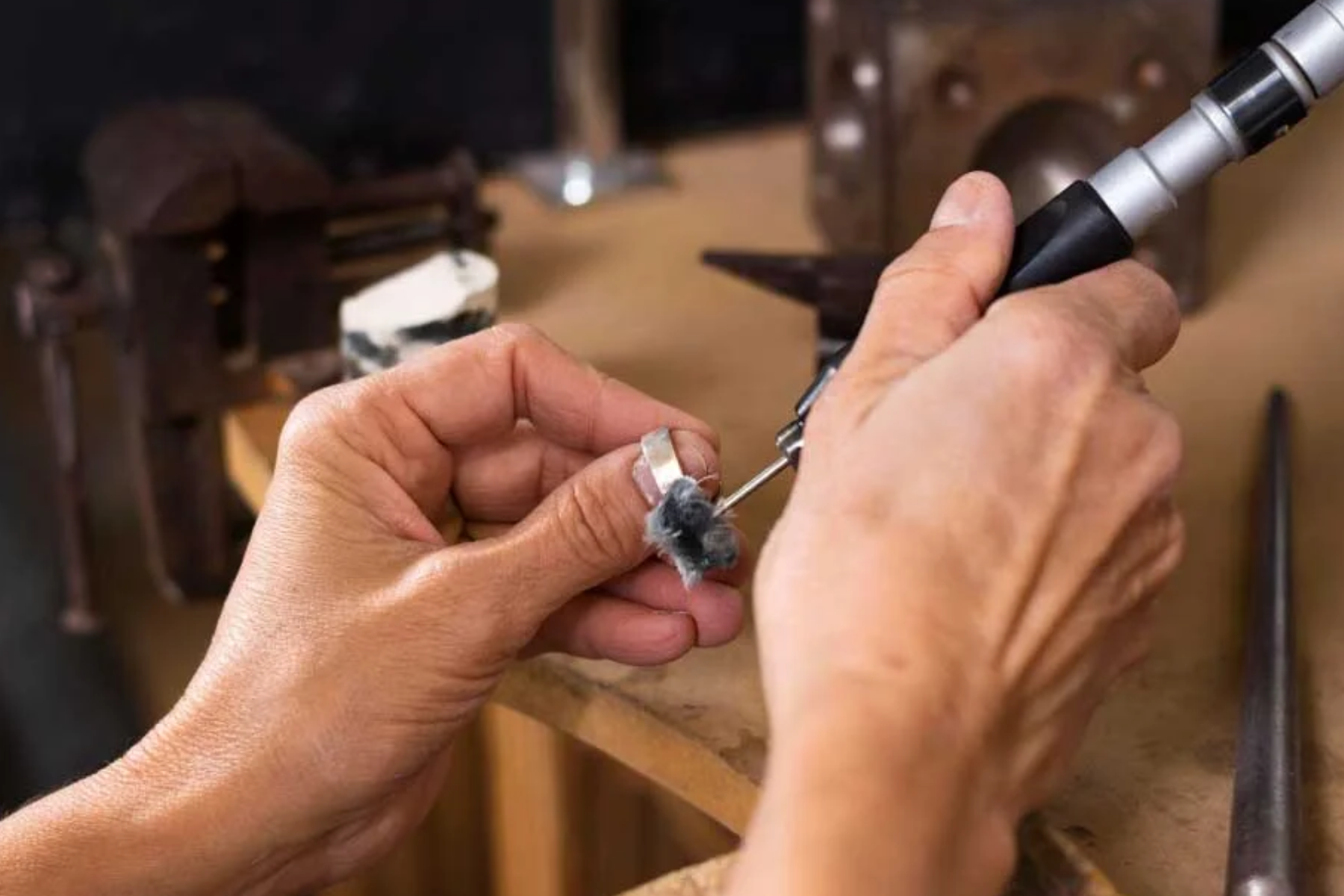 A man's hand engraving a ring with a machine