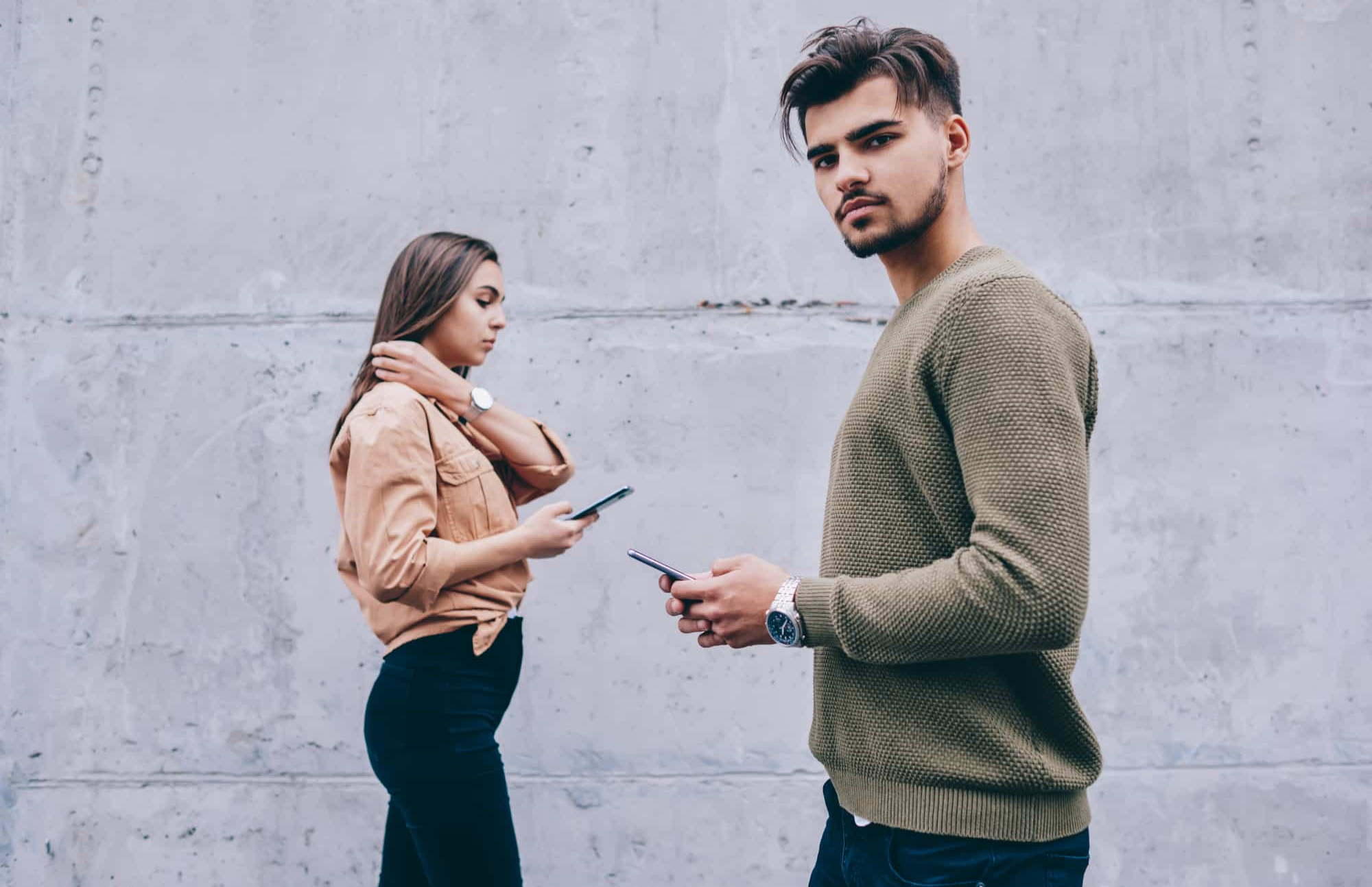 A Cancerian man walks while clutching a phone and ignoring a girl who is also carrying a phone