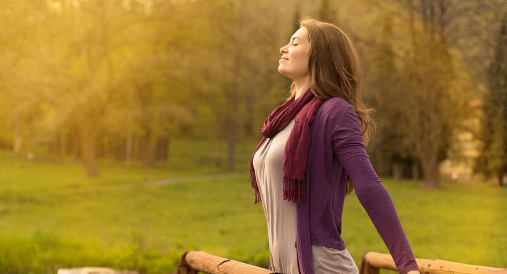 A woman is releasing her stress in a peaceful and refreshing setting with plenty of trees and fresh air