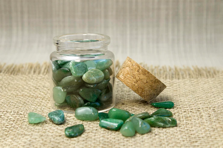Green Aventurine stone in glass bottle and some out of the bottle