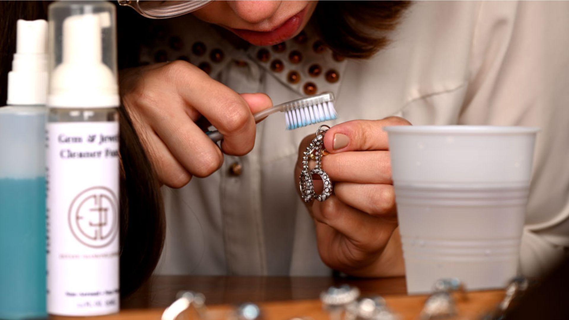 Woman Cleaning Silver Earing With Toothbrush