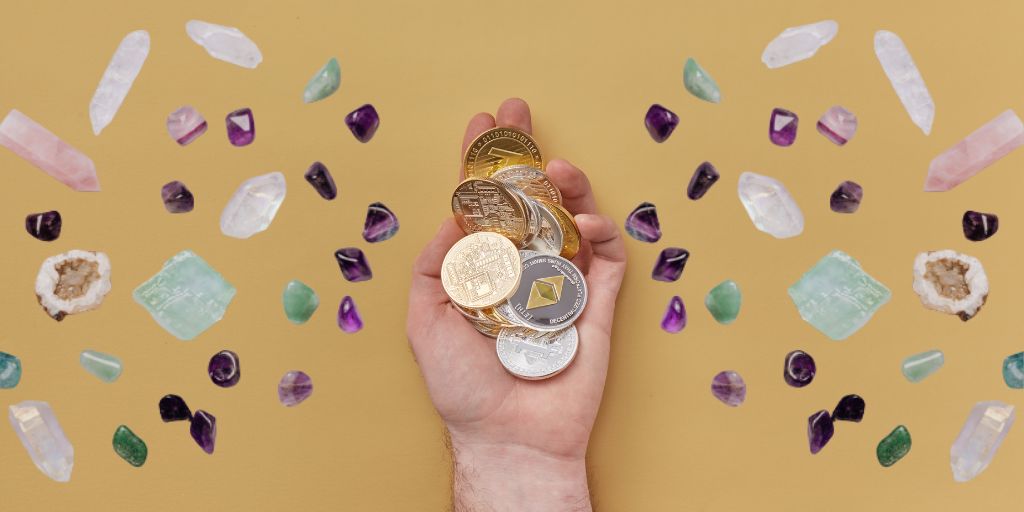 A hand full of coins with different kinds of crystals around
