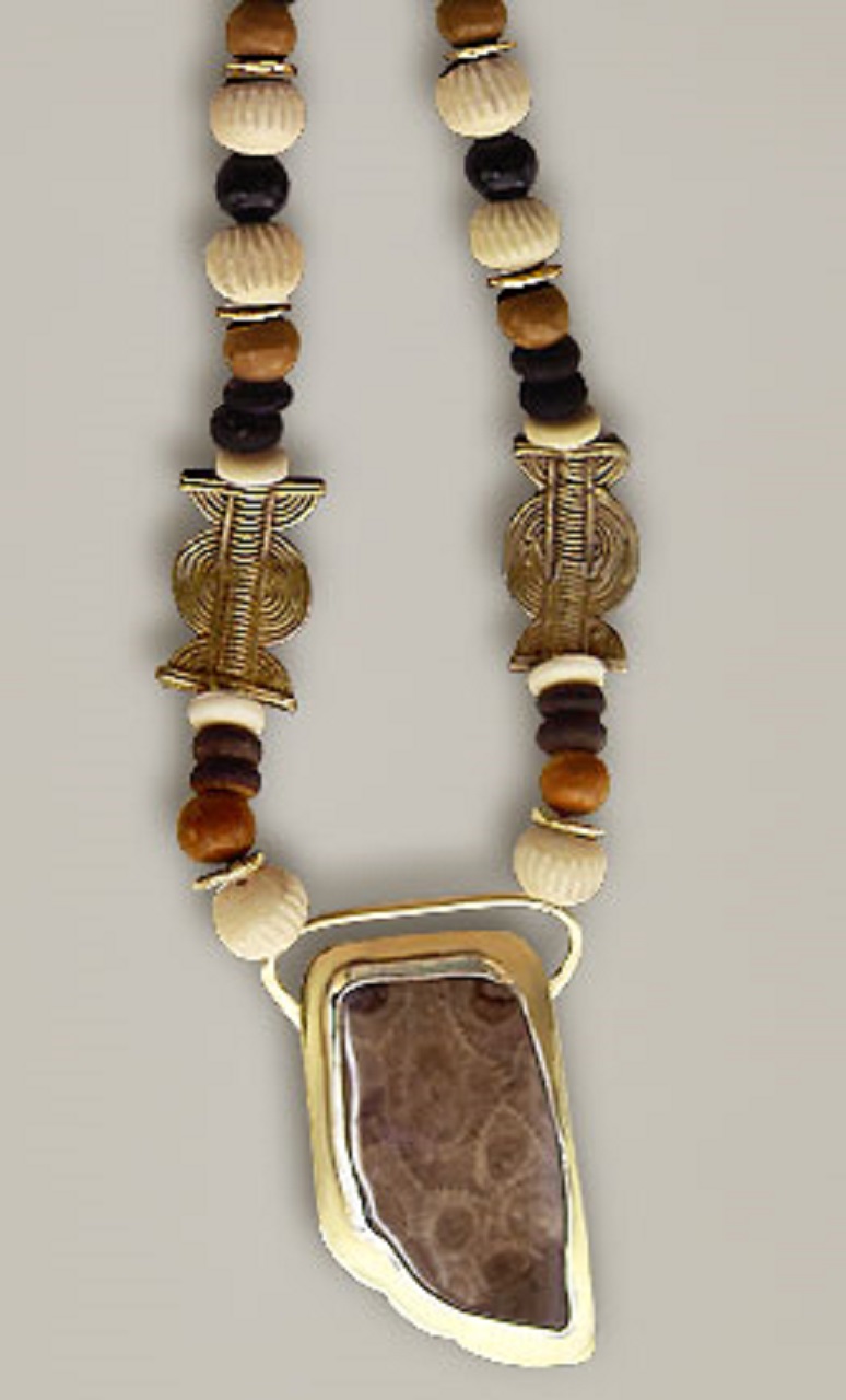 An irregular shaped pendant with black, white and brown onyx beads and brass beads