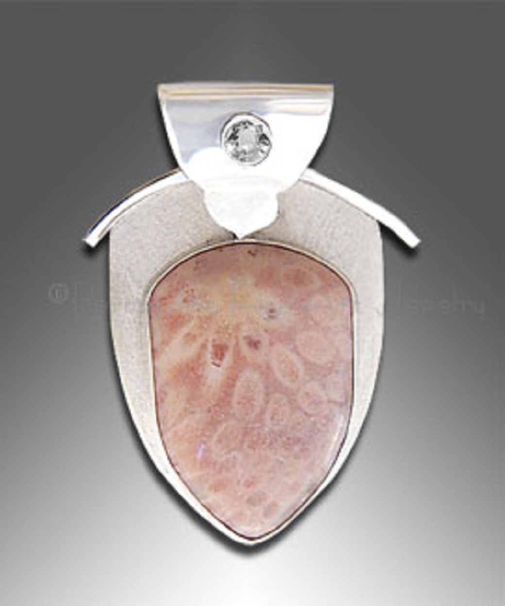 A silver pendant with pink coral fossil and a small round white topaz at the top