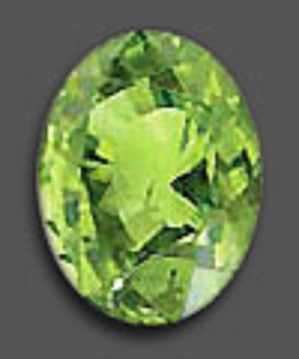 A polished oval-shaped zircon in bright green and with several facets