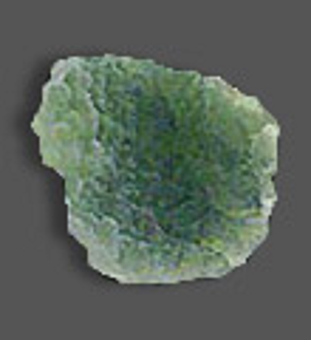 A rough piece of moldavite with rough edges and a darker shade of green on its middle part