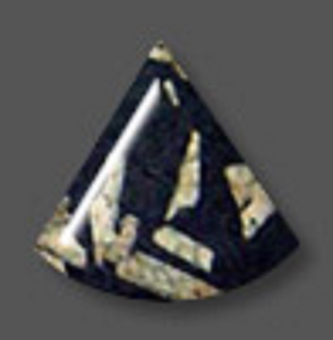 A triangular black Chinese Writing Stone with a curved bottom and some irregular-shaped beige patches