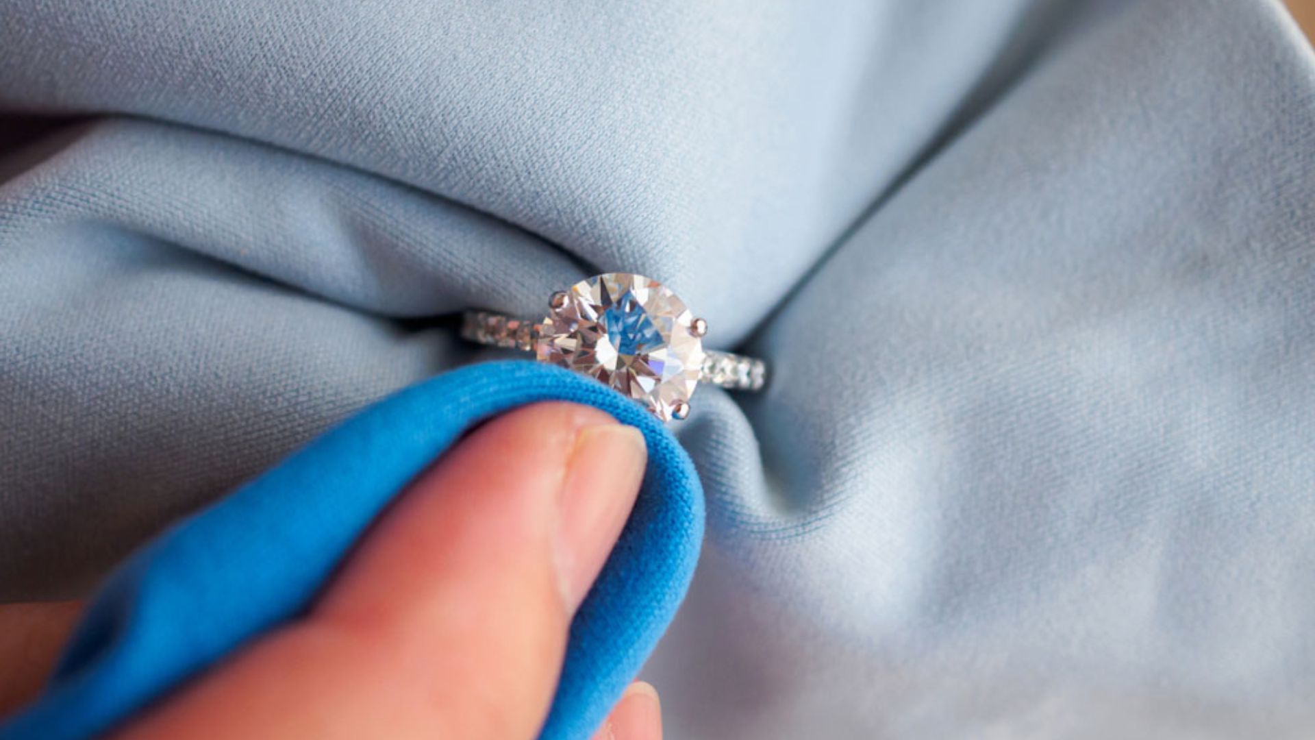 Woman Cleaning A Diamond Ring With Blue Towel